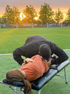 Dr. Paul performing an adjustment to the lower back of an athlete on the field, located in Louisville, CO